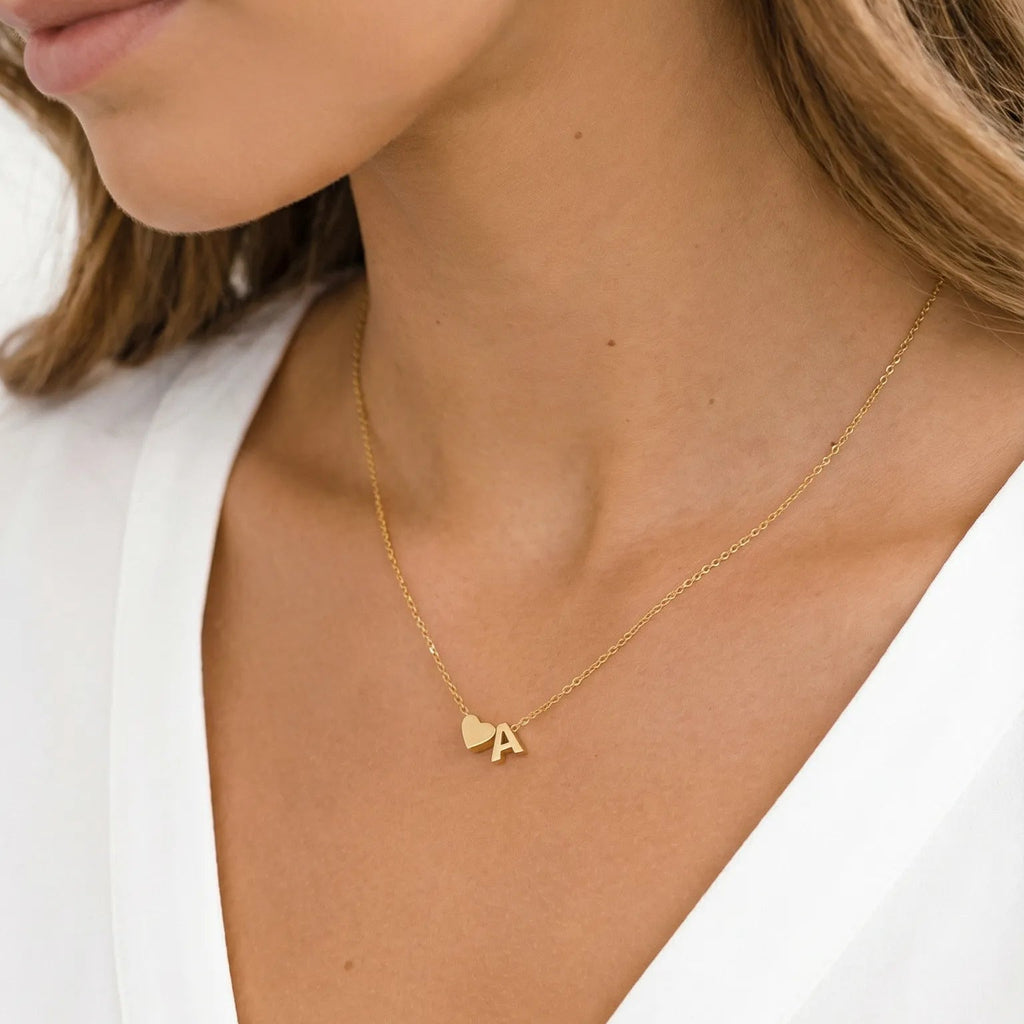 Gold necklace with a heart pendant worn by a person in a white top.