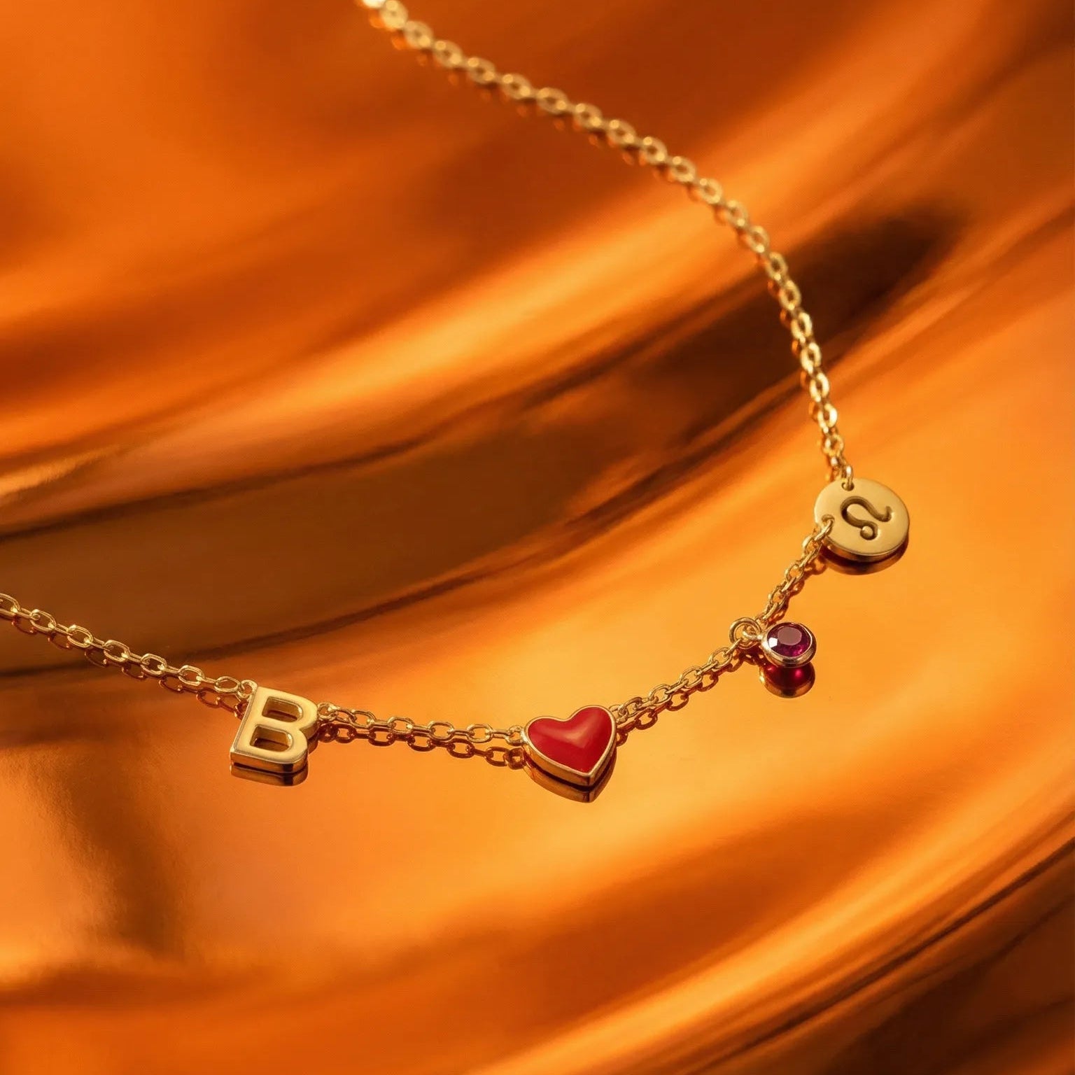 Gold necklace with heart and letter 'B' charms on an orange satin background