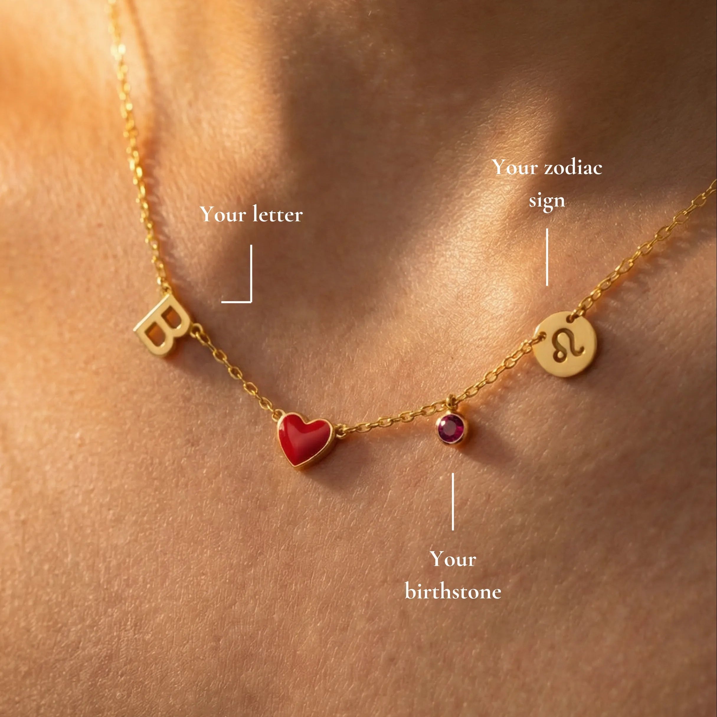 Gold necklace with heart, letter, and zodiac sign charms on a person's neck.